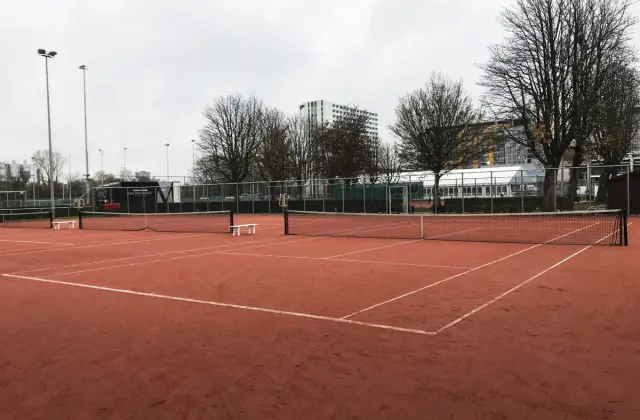 Cancha de tenis de superficie roja con la red instalada