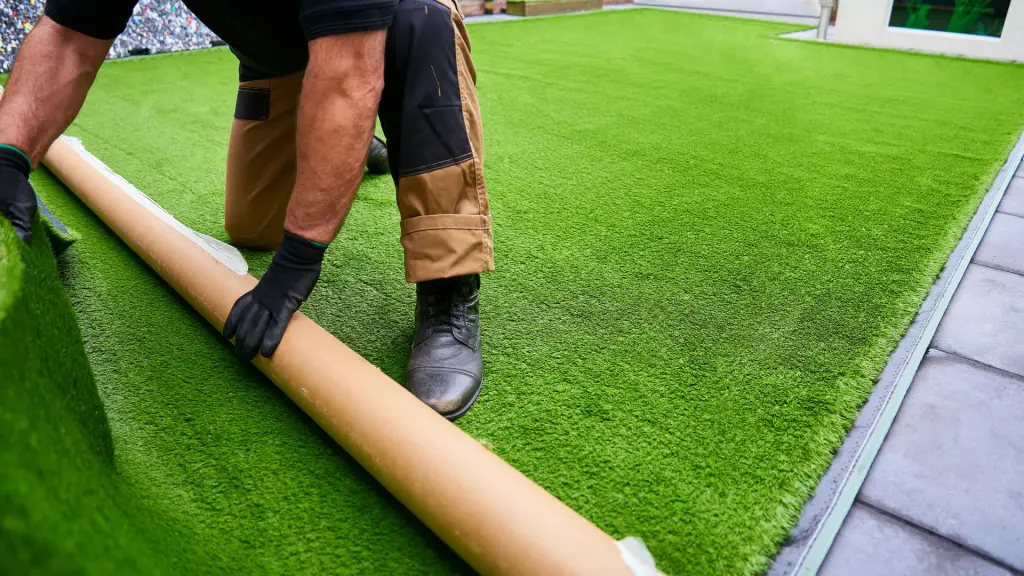 Instalador desenrollando un rollo de césped artificial